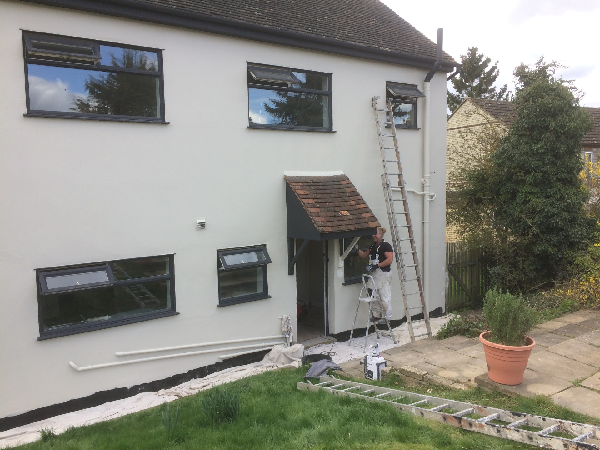 Decorator painting the exterior render and window frames of a family home